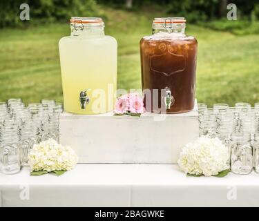 Drink table with lemonade, iced tea, glasses and flowers on a shabby chic table at an outdoor elegant event in the countryside.. Stock Photo