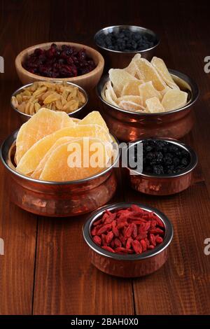 Slices of candied ginger root, pieces of dried mango fruits, dried blueberries and goji berries, dried cranberries, golden and blue raisins in small b Stock Photo