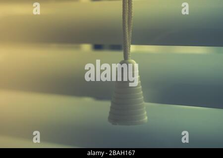 rope blinds with plastic cap close-up on a background of horizontal shutters. Stock Photo