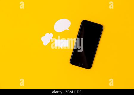 Smartphones with paper speech bubbles on yellow background. Communication concept. Top view. Copy space. Paper composition Stock Photo