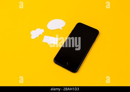 Smartphones with paper speech bubbles on yellow background. Communication concept. Top view. Copy space. Paper composition Stock Photo