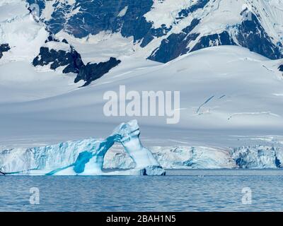 A huge iceberg arch in the Gerlache strait of the Antarctica peninsula as seen from an expedition ship Stock Photo