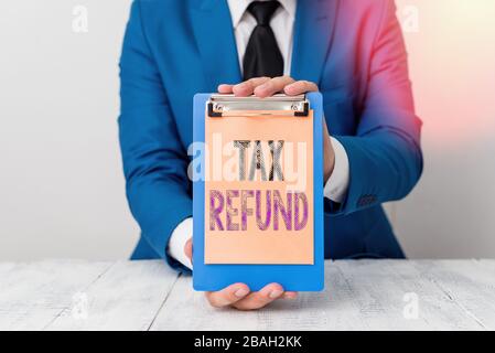 Conceptual hand writing showing Tax Refund. Concept meaning refund on tax when the tax liability is less than the tax paid Man holds empty paper with Stock Photo