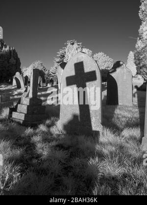 The shadow of a cross falls on an old gravestone.  Taken in near-infrared (720nm). Stock Photo