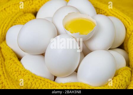 white chicken eggs in yellow wool sweater. lot of white eggs close up. broken chicken white egg. Stock Photo