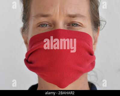 Caucasian woman poses for the camera with her DIY face mask (made from an old t-shirt sleeve) during the 2019-20 corona-virus pandemic. Stock Photo