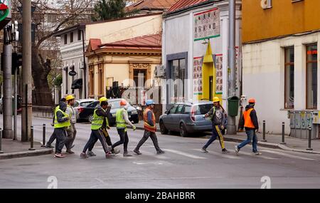Bucharest, Romania - March 22, 2020: Construction workers cross the street, llike the Beatles on Abbey Road, in Bucharest, Romania. This image is for Stock Photo