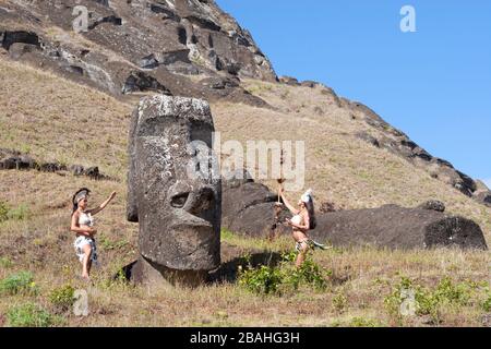 Rapa Nui dancers in traditional costume paying tribute to old giant stone head in Rano Raraku moai quarry on Easter Island Stock Photo