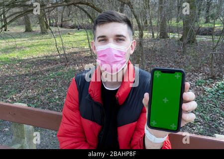 Man in medical mask hold cellphone with green empty screen. Epidemic new rapidly spreading coronavirus 2019-ncov medicine flu virus concept Stock Photo
