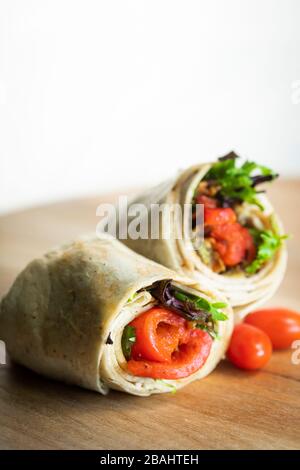 A fresh tasty roasted red pepper and turkey wrap displayed on a wooden cutting board Stock Photo