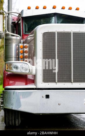 Big rig bonnet diesel industrial wet semi truck chrome accessories standing on the parking in raining weather for cargo load f Stock Photo - Alamy