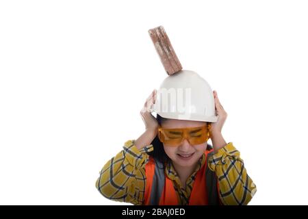 The stick block brick fell on the Asia engineer young woman head on the helmet worker at white background, Area construction safety first concept Stock Photo