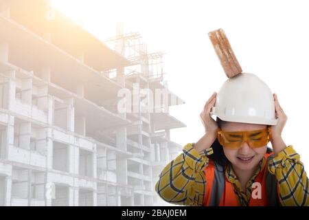 The stick block brick fell on the Asia engineer young woman head on the helmet worker at white background, Area construction safety first concept Stock Photo