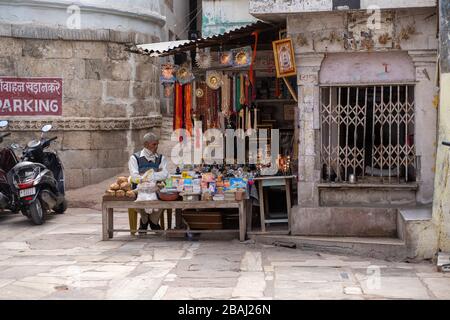 Eklingji, India - March 15, 2020: Vendor sits at his market stall stand, selling, books, trinkets and jewelry, waiting for customers Stock Photo