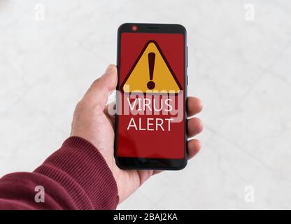 Virus alert message on red background on smartphone. Concept of warning in technology. Stock Photo