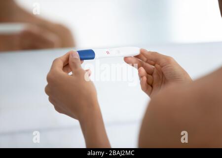 Closeup view over shoulder of woman holding positive pregnancy test Stock Photo