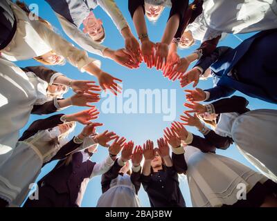 Students graduates make the shape of a circle from the palms of their hands. Stock Photo