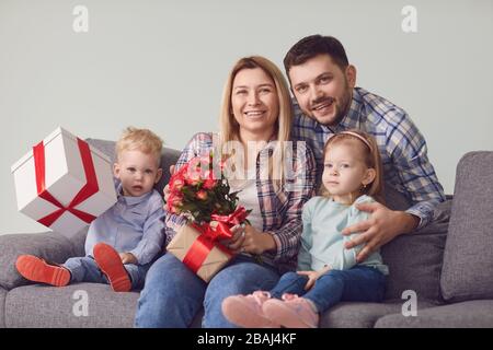 Happy funny family giving presents while sitting on sofa at home. Stock Photo