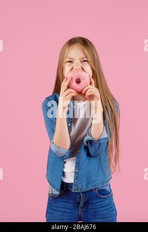 girl playing with a donut on a pink background Stock Photo