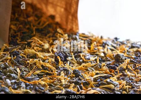 Herbal tea closeup. Multi coloured dried herbal tea leaves and brown kraft paper bag with selective focus. Stock Photo