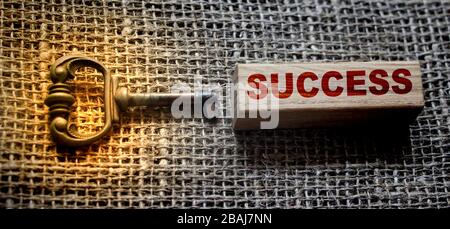 Vintage Key and success word on wooden block on burlap canvas. Key to success concept Stock Photo