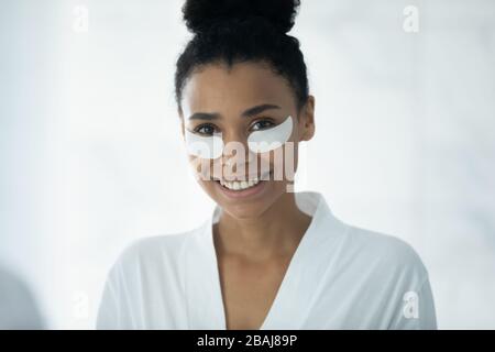 African woman using hydrogel recovery patches for perfect undereye skin Stock Photo