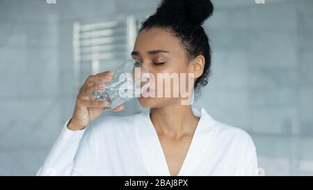 African woman holding glass drinking still water in the morning Stock Photo