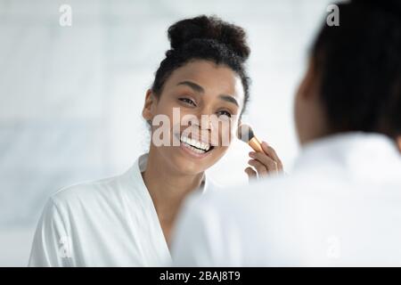 African young woman holds brush applying make up Stock Photo
