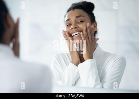 Beautiful african woman touch face enjoys perfect face skin Stock Photo