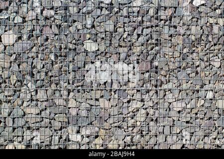 Gabion rock wall, stones in steel wire cage, decoration rocks cube in garden Stock Photo