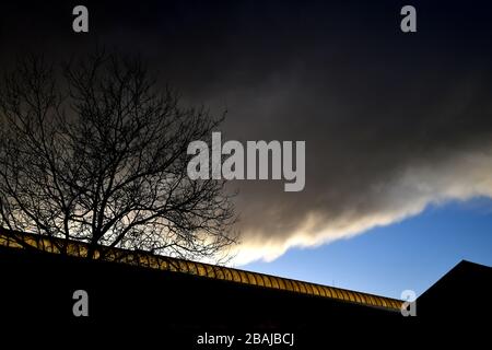 The glass roof of Zwolle train station lightens up as a result of the setting sun, while at the same time a pitch black rainclouds hangs over Stock Photo
