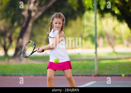 Child playing tennis on indoor court. Little girl with tennis racket and ball in sport club. Active exercise for kids. Summer activities for children. Stock Photo