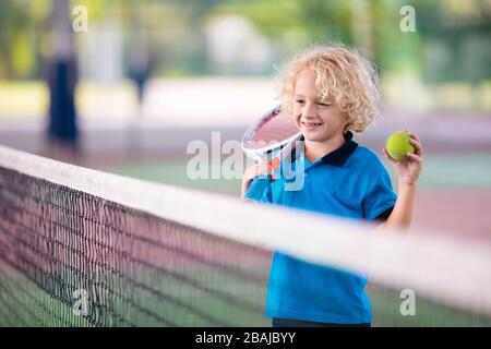 Child playing tennis on indoor court. Little boy with tennis racket and ball in sport club. Active exercise for kids. Summer activities for children. Stock Photo