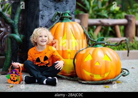 Child in Halloween costume. Kids trick or treat. Little boy dressed with pumpkin lantern. Family celebration. Stock Photo