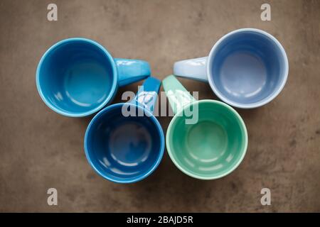 four tea mugs of different colors on a gray background Stock Photo