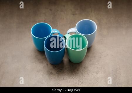 four tea mugs of different colors on a gray background Stock Photo