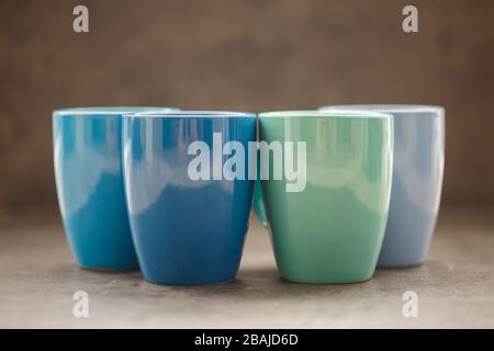 four tea mugs of different colors on a gray background Stock Photo