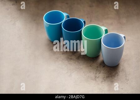 four tea mugs of different colors on a gray background Stock Photo