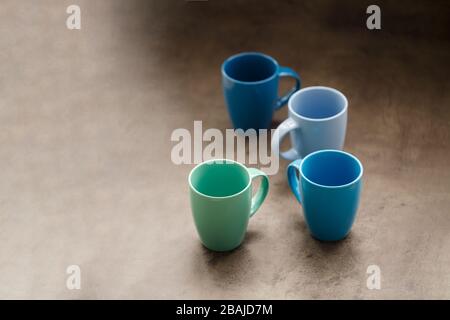 four tea mugs of different colors on a gray background Stock Photo