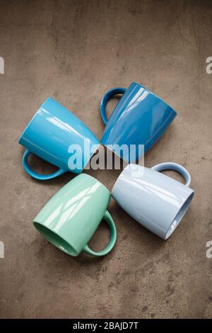 four tea mugs of different colors on a gray background Stock Photo