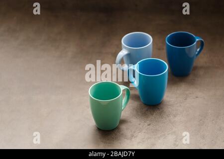 four tea mugs of different colors on a gray background Stock Photo