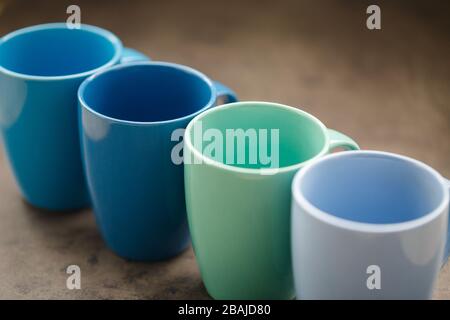 four tea mugs of different colors on a gray background Stock Photo