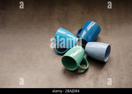 four tea mugs of different colors on a gray background Stock Photo