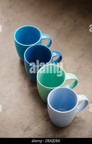 four tea mugs of different colors on a gray background Stock Photo