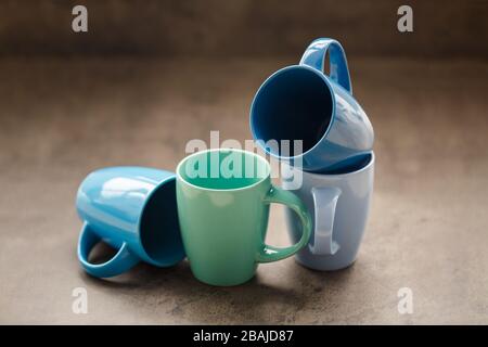 four tea mugs of different colors on a gray background Stock Photo
