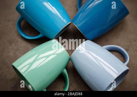 four tea mugs of different colors on a gray background Stock Photo