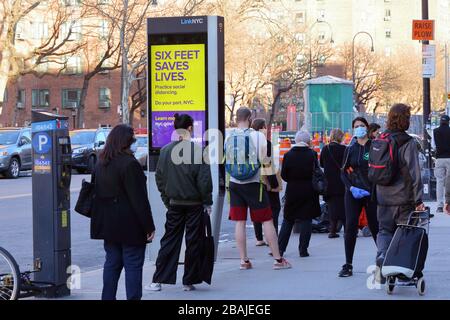 New York, NY, 27th March 2020. New Yorkers wearing protective masks practicing social distancing as they queue... SEE MORE INFO FOR FULL CAPTION Stock Photo