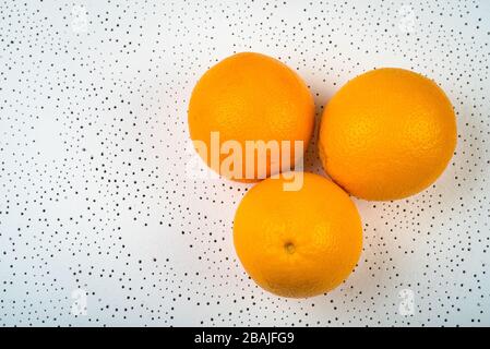 three whole oranges are dotted on a white surface. background. juicy citrus fruits Stock Photo