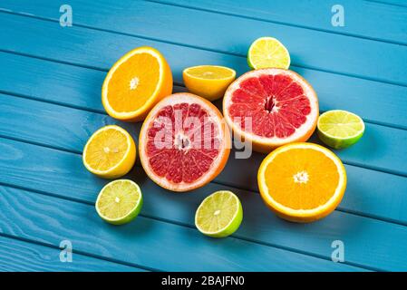 juicy oranges, grapefruits, limes and lemons lie on a blue wooden table. citrus fruits vitamins Stock Photo