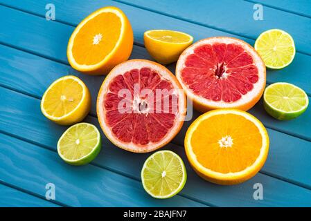 bright and juicy oranges, grapefruits, limes and lemons lie on a blue wooden table. citrus fruits, vitamins. Stock Photo